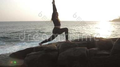 女孩剪影练习瑜伽锻炼站在岩石上
